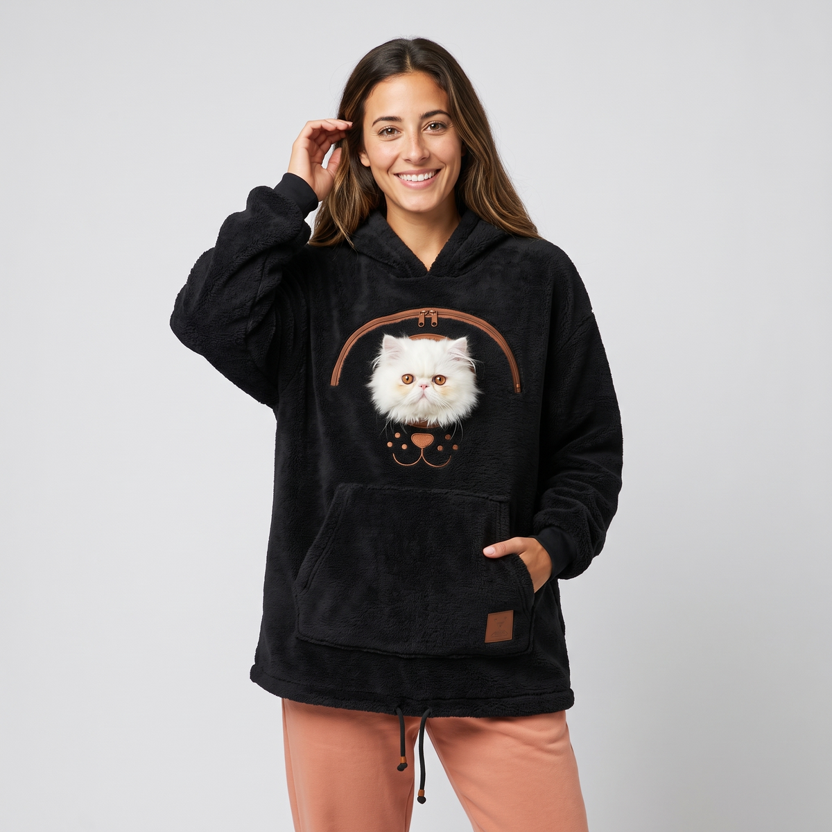 Woman wearing the black CozyPaws pet pocket hoodie with a white Persian kitten peeking out of the chest window